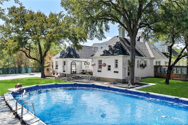 rear view of property with a fenced in pool and a yard