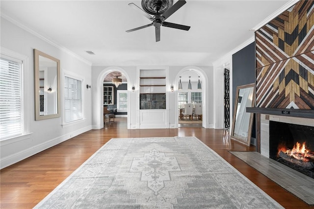 living room featuring crown molding, a wealth of natural light, dark wood-type flooring, and ceiling fan