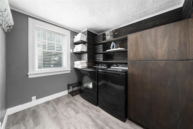 clothes washing area with light hardwood / wood-style floors and washer and clothes dryer