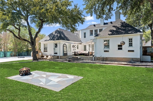 rear view of house with a lawn, a patio area, and an outdoor living space with a fire pit