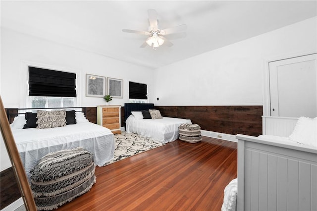 bedroom featuring ceiling fan, hardwood / wood-style floors, and wooden walls