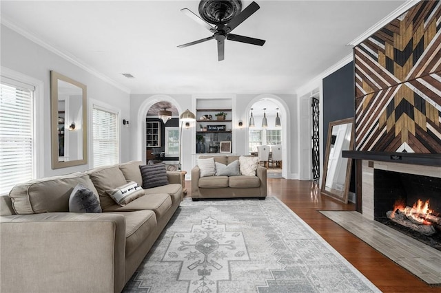 living room with a fireplace, hardwood / wood-style floors, ornamental molding, and a healthy amount of sunlight