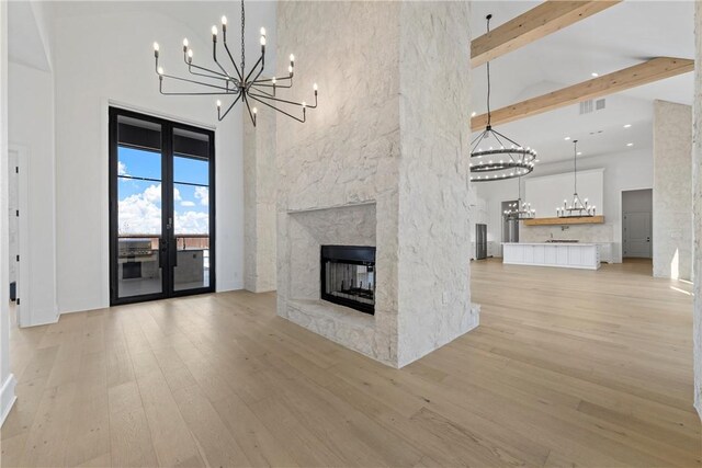 entrance foyer with a high ceiling, an inviting chandelier, a premium fireplace, light hardwood / wood-style flooring, and ornamental molding