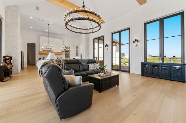 living room featuring a healthy amount of sunlight, light hardwood / wood-style floors, a towering ceiling, and a chandelier