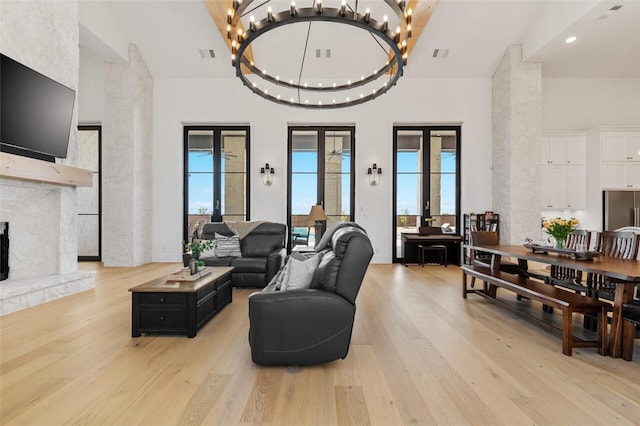 living room featuring a fireplace, french doors, light hardwood / wood-style floors, and an inviting chandelier