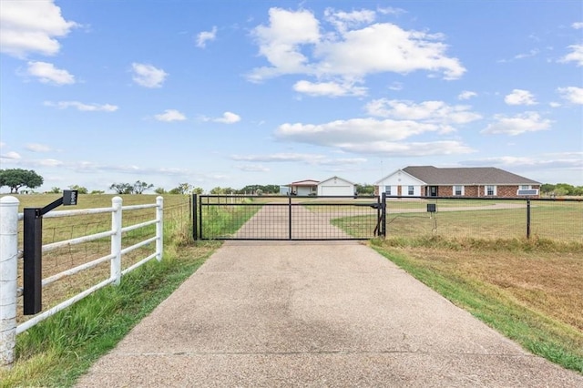 view of gate with a lawn and a rural view