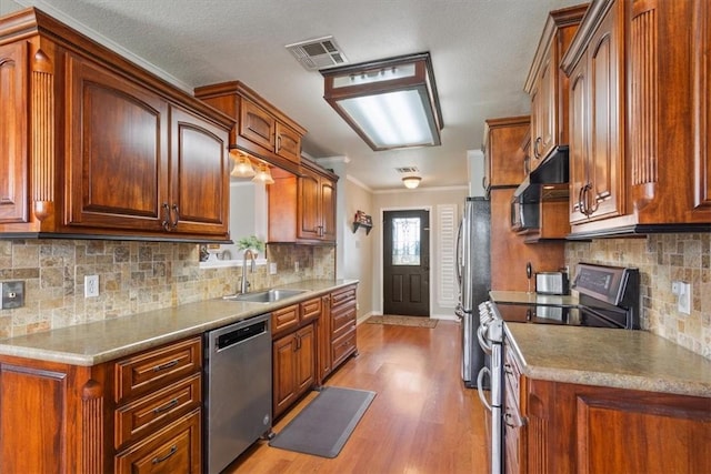 kitchen featuring tasteful backsplash, sink, stainless steel appliances, and light wood-type flooring