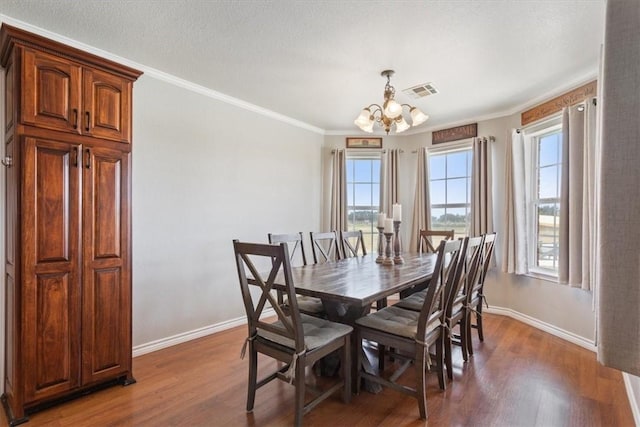 dining room with a textured ceiling, dark hardwood / wood-style flooring, an inviting chandelier, and crown molding