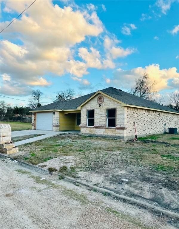 view of front of home featuring an attached garage, stone siding, concrete driveway, and roof with shingles