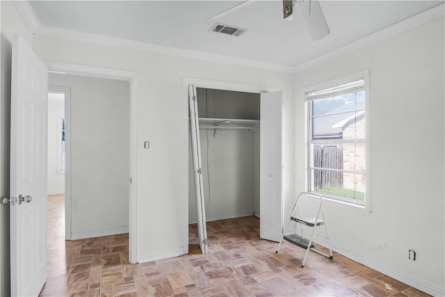 unfurnished bedroom featuring multiple windows, a closet, crown molding, and ceiling fan