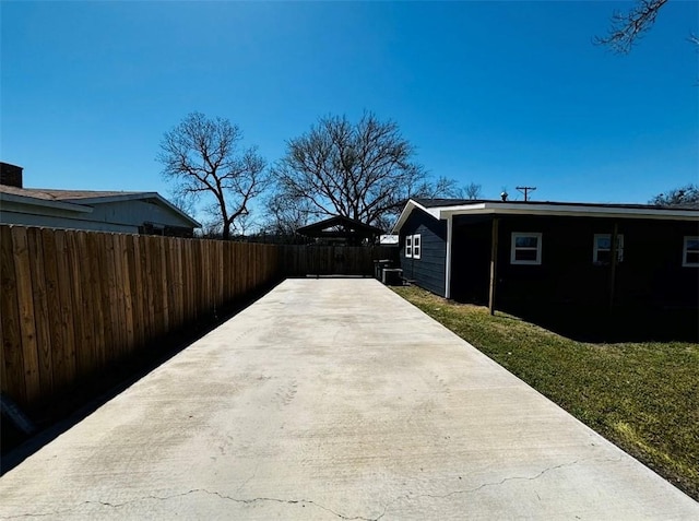 view of home's exterior featuring a patio, concrete driveway, and fence