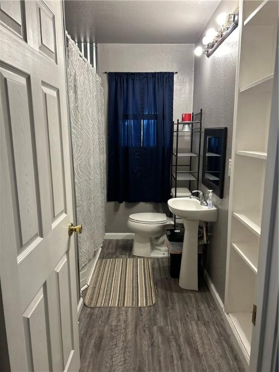 bathroom featuring a shower with curtain, baseboards, toilet, and wood finished floors