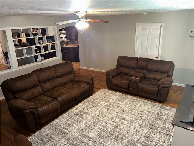 living room featuring ceiling fan, baseboards, a textured ceiling, and wood finished floors