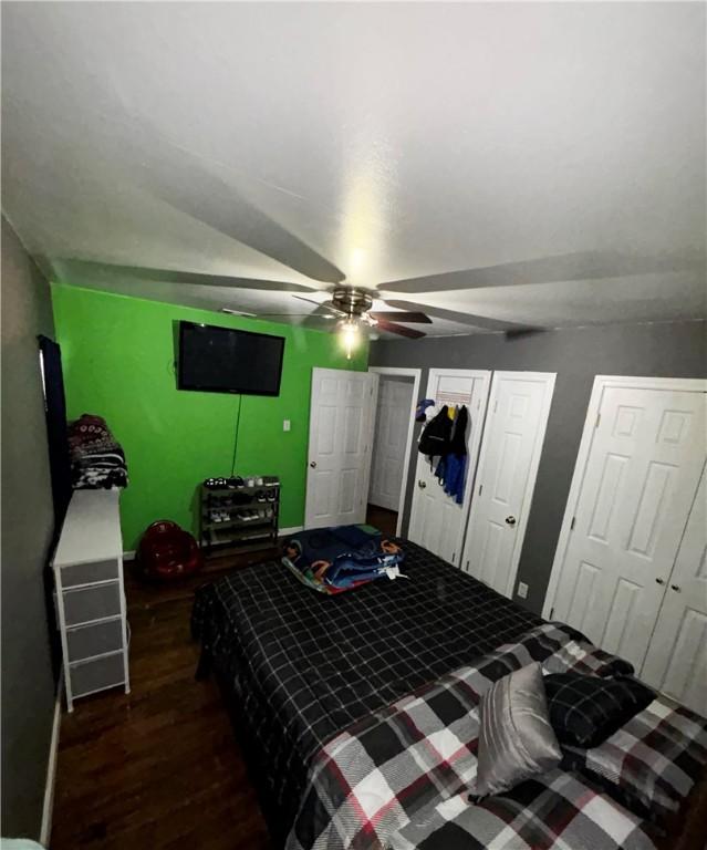 bedroom featuring two closets, a ceiling fan, and wood finished floors