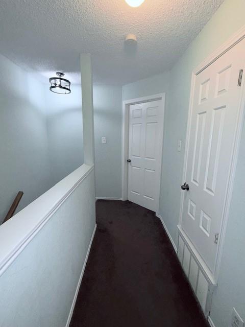 corridor featuring dark colored carpet