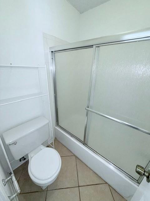 bathroom with tile patterned floors, toilet, and a shower with shower door