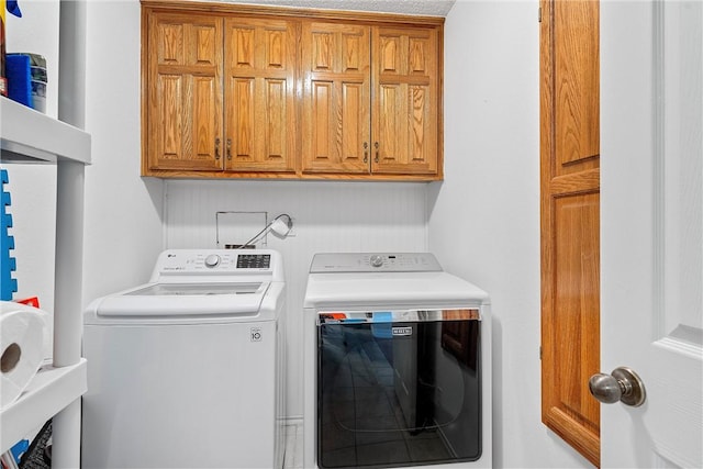 laundry room with washing machine and clothes dryer and cabinets