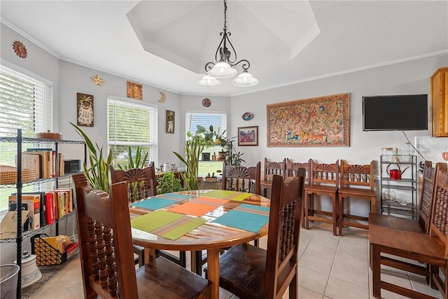 tiled dining room featuring a chandelier, ornamental molding, and a tray ceiling