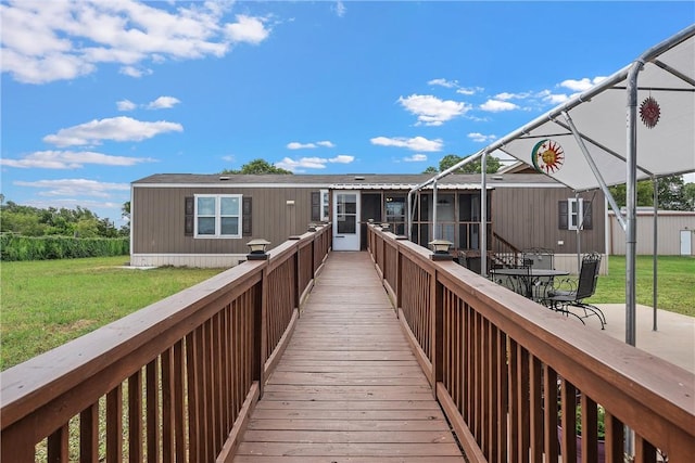 back of property featuring a lawn, glass enclosure, and a deck