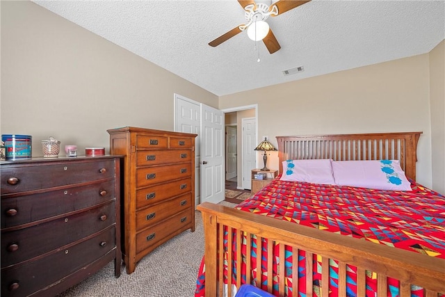 bedroom with a textured ceiling, ceiling fan, and light carpet