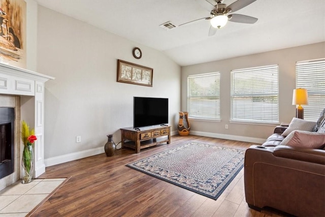 living room with light hardwood / wood-style floors, lofted ceiling, and a tiled fireplace