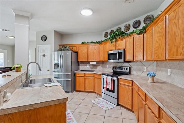 kitchen with backsplash, sink, light tile patterned floors, and stainless steel appliances