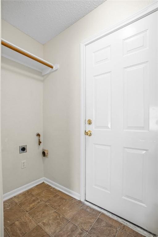 laundry room featuring hookup for an electric dryer, a textured ceiling, and dark tile patterned floors