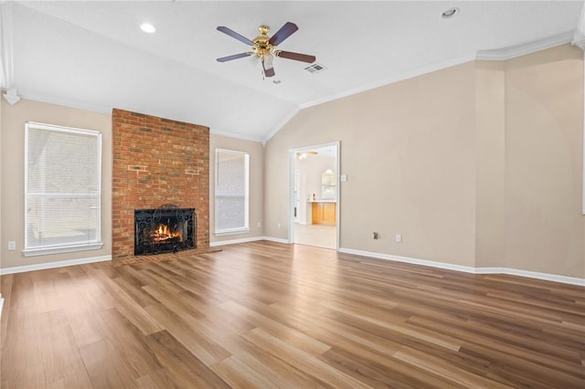 unfurnished living room with hardwood / wood-style floors, vaulted ceiling, a brick fireplace, and crown molding