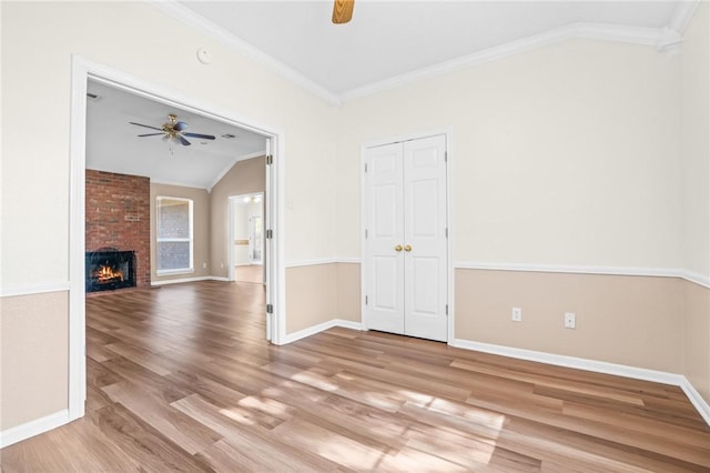 unfurnished living room with ornamental molding, ceiling fan, light hardwood / wood-style flooring, a fireplace, and lofted ceiling