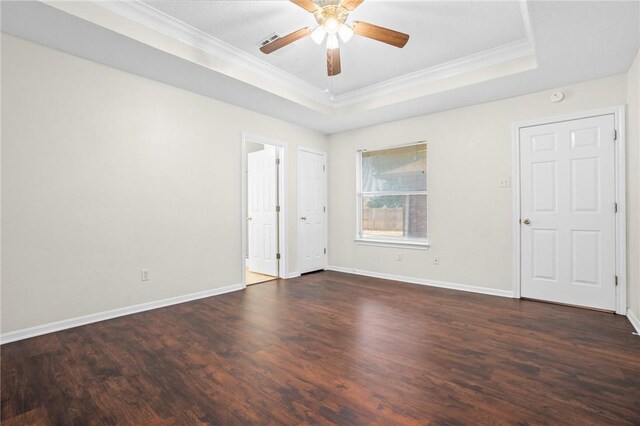 unfurnished room featuring a tray ceiling, crown molding, ceiling fan, and dark wood-type flooring