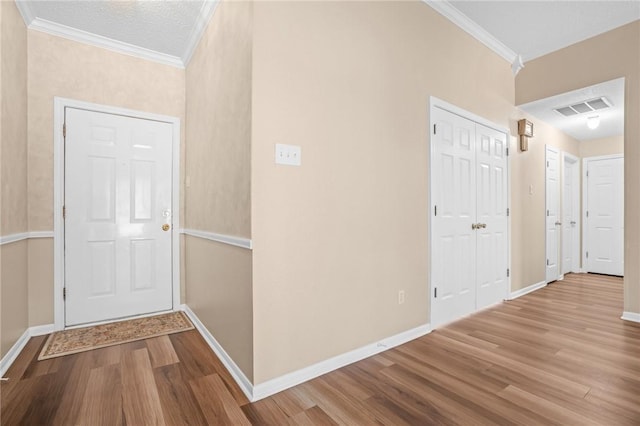 hallway featuring light hardwood / wood-style floors, a textured ceiling, and ornamental molding