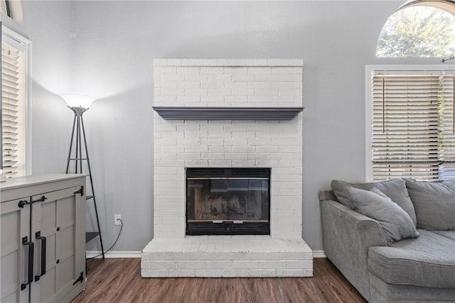 living room with dark hardwood / wood-style flooring and a brick fireplace