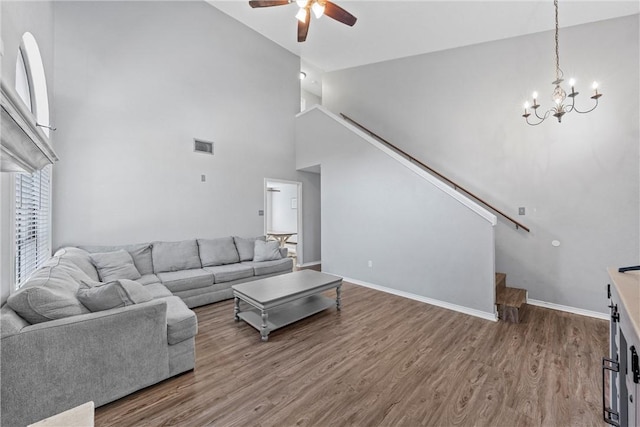 living room with ceiling fan with notable chandelier, wood-type flooring, and high vaulted ceiling