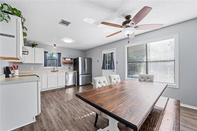 dining space with a textured ceiling, ceiling fan, dark wood-type flooring, and sink