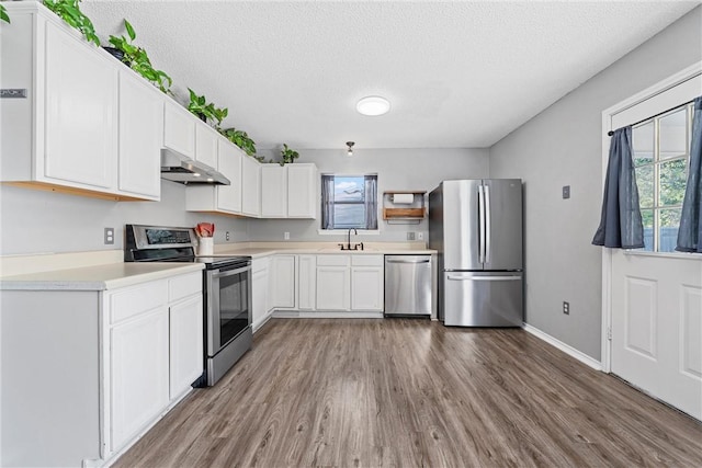 kitchen featuring white cabinetry, sink, wood-type flooring, a textured ceiling, and appliances with stainless steel finishes