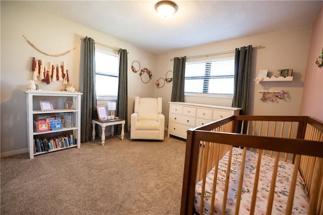 bedroom with multiple windows, a nursery area, and carpet floors