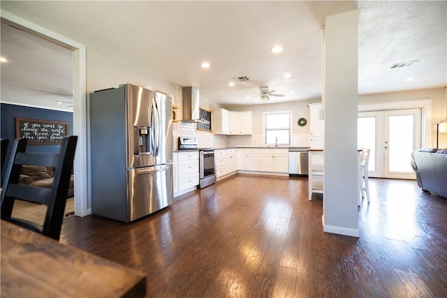 kitchen featuring visible vents, appliances with stainless steel finishes, dark wood-type flooring, and wall chimney range hood