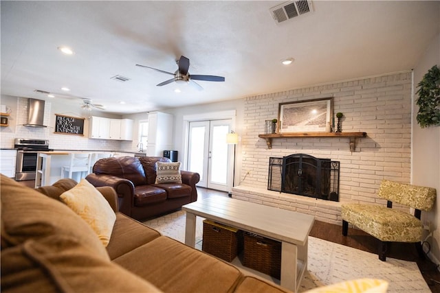 living area with ceiling fan, visible vents, wood finished floors, and a fireplace