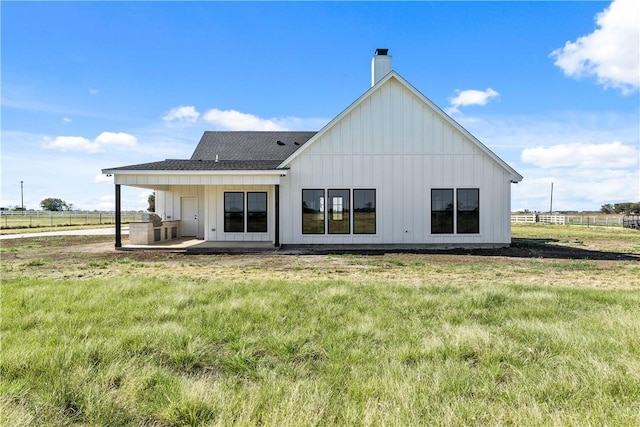 rear view of house with a yard, a patio, and a rural view