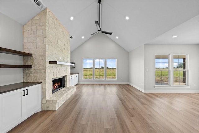 unfurnished living room with plenty of natural light, ceiling fan, light wood-type flooring, and a fireplace