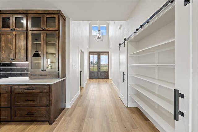 hall featuring a barn door, a chandelier, and light wood-type flooring