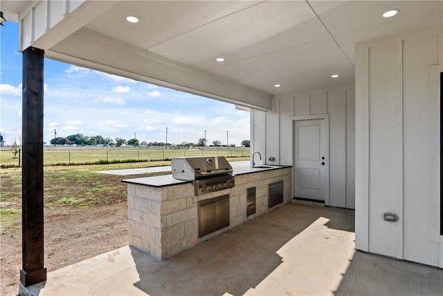 view of patio / terrace featuring area for grilling, sink, a rural view, and an outdoor kitchen