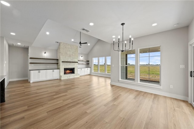 unfurnished living room with a stone fireplace, light wood-type flooring, high vaulted ceiling, and a chandelier