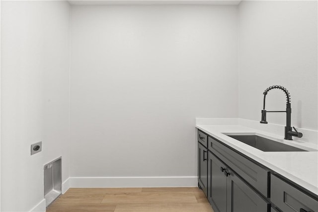 clothes washing area featuring hookup for an electric dryer, light hardwood / wood-style floors, and sink