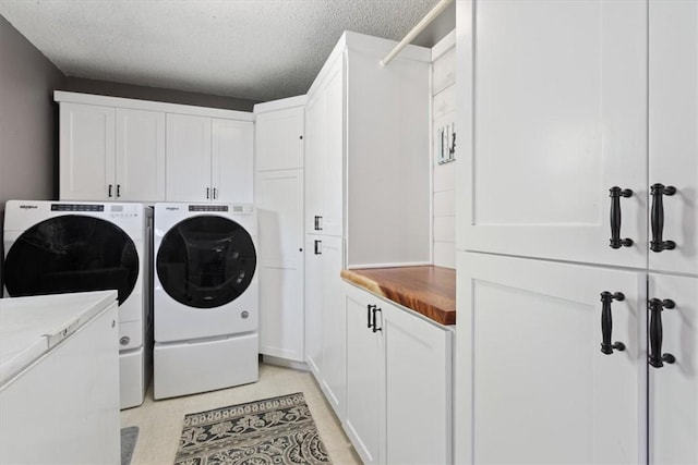 laundry room featuring washing machine and dryer, cabinets, and a textured ceiling