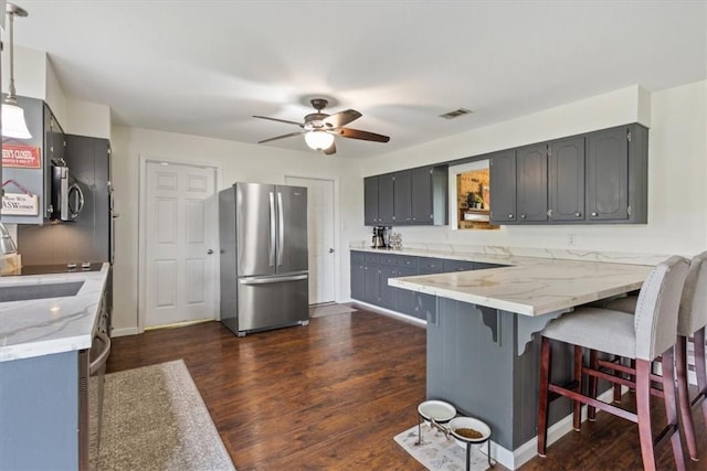 kitchen featuring sink, dark hardwood / wood-style floors, stainless steel fridge, ceiling fan, and kitchen peninsula