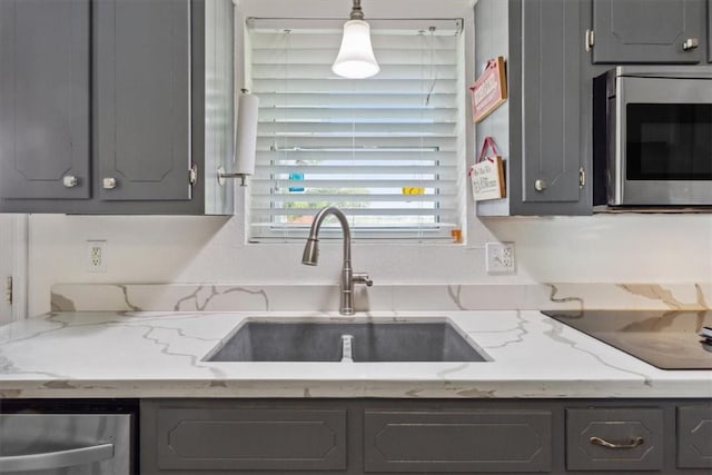 kitchen with gray cabinets, light stone counters, sink, and hanging light fixtures