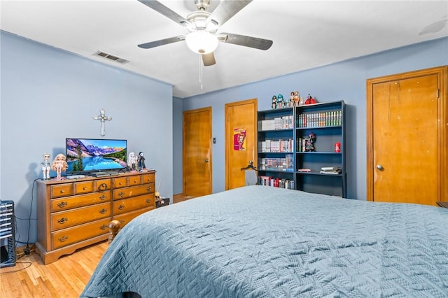 bedroom with hardwood / wood-style floors, two closets, and ceiling fan