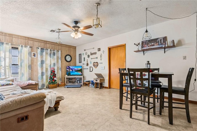 living room with ceiling fan, wooden walls, and a textured ceiling