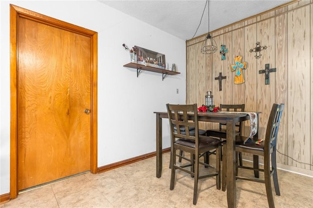 dining room featuring a textured ceiling and wood walls